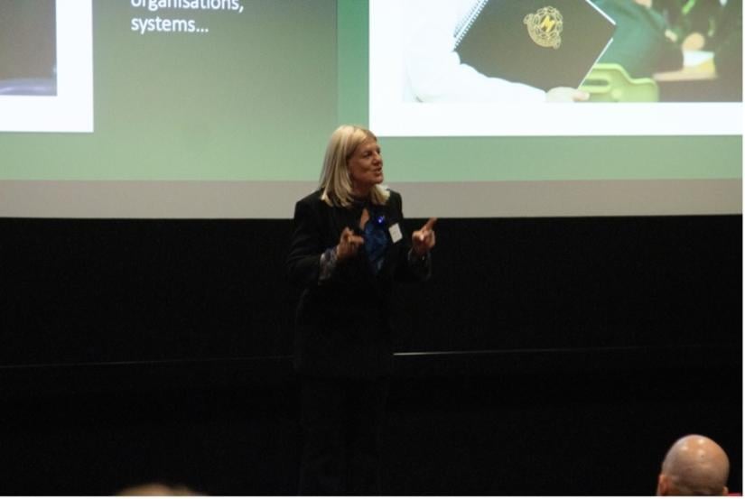 A blonde haired woman speaks to an unseen crowd