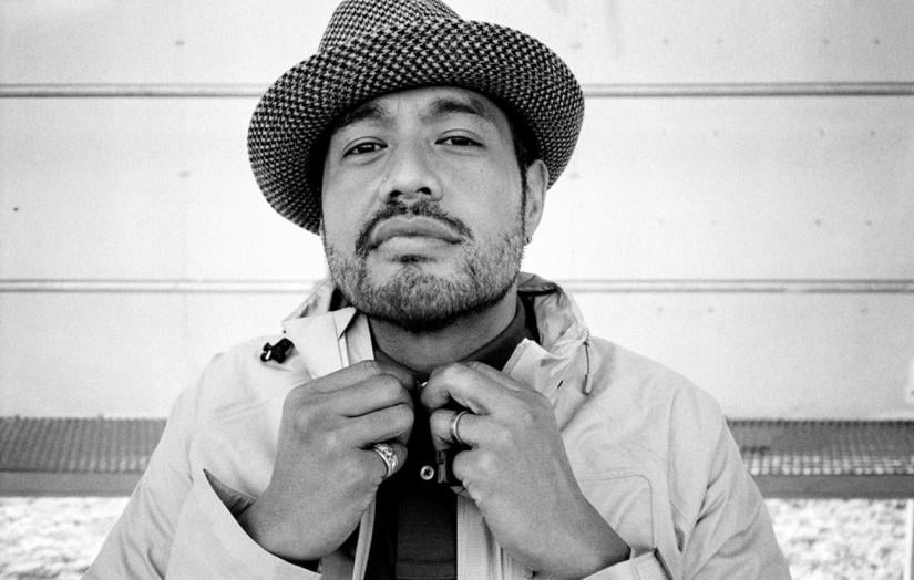 black and white image of male person wearing a hat and smiling slightly at camera