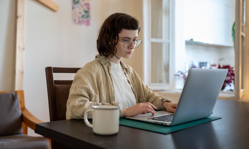 A focused woman with glasses working at laptop