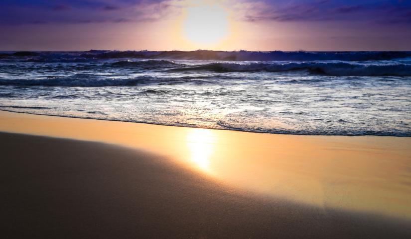 The sun close to the horizon over an ocean beach. Picture by Martin Snicer on Flickr, CC BY-ND 2.0