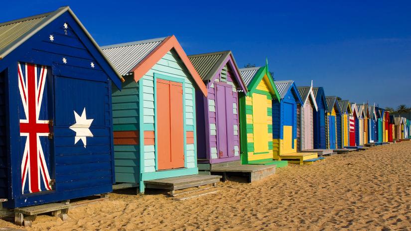 A row of colourful painted shacks on a beach