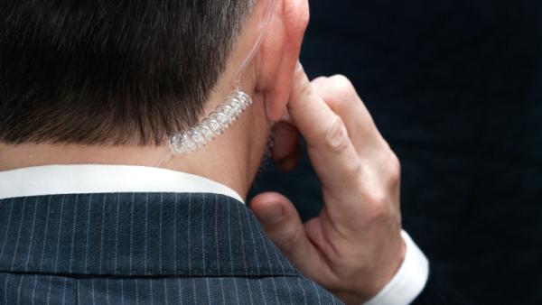 800x450 Close-up of a secret service agent listening to his earpiece, behind