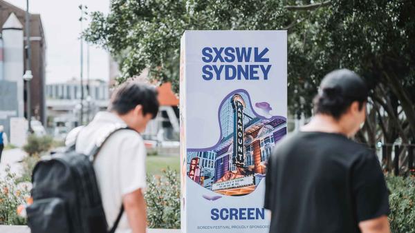 People walking past a sign for the SXSW Sydney Screen Festival