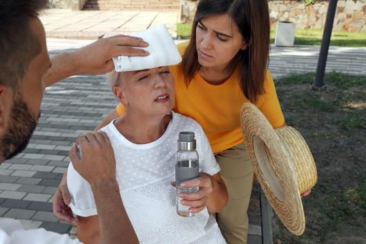 Stock picture of a woman suffering heat stroke being tended to by two other people