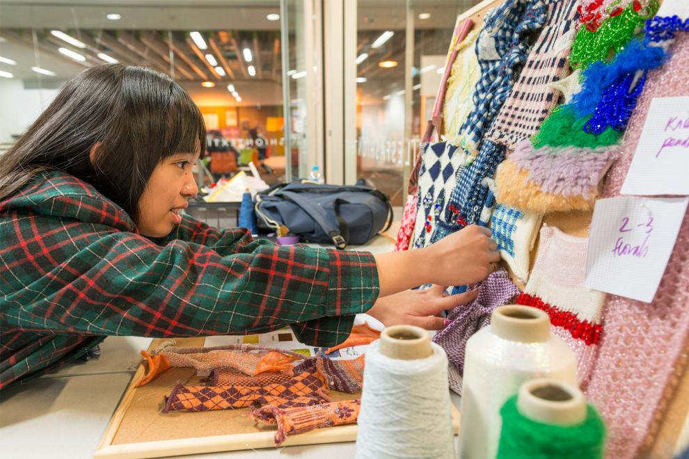 Student making a craft board of different woollens and fabrics.