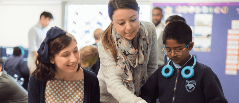 Two women help a child read a book in a classroom