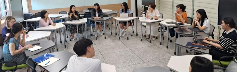 people sitting in a classroom at desks in a circle facing each other