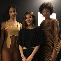 Jessica Xie smiling, between two models wearing looks from her fashion collection.