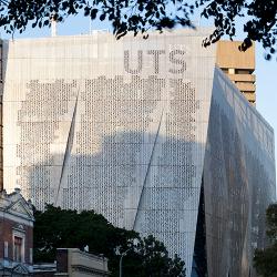 A large, rectangular building covered in aluminum screens with a perforated binary code
