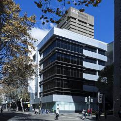 A square 5-level building with dark windows and a shiny metallic-grey facade, on the corner of Harris St and Thomas St.