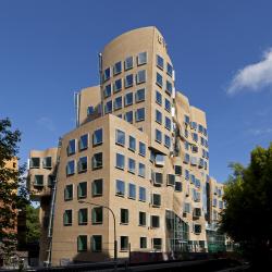 A brown brick building with multiple segments, curved walls and large square windows