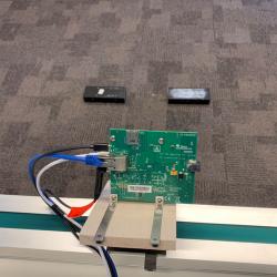 A green motherboard with cables in the foreground, with two black boxes (targets) in the distance
