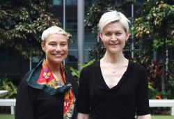 Two women standing side by side and smiling at the camera