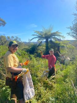 Daniel with two other people working in a field in Barcelona wearing gloves and holding bags.