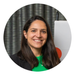 Dr Mariana Sousa has long brown hair and brown eyes. she is wearing a bright green top under a black jacket. She is smiling at the camera.