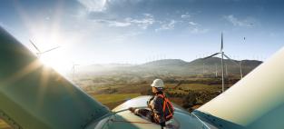 Technician sitting atop a large wind turbine in a wind farm