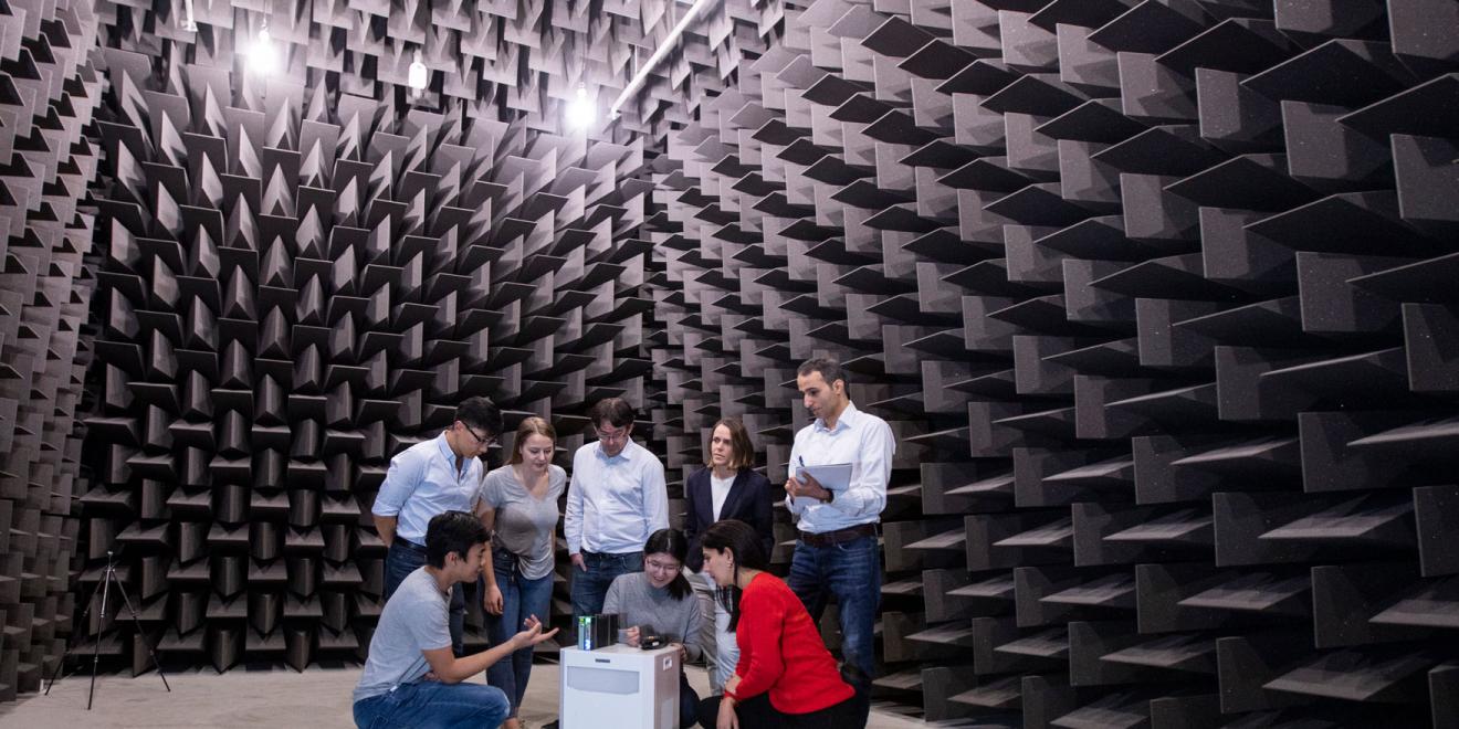 A group of people crouched over their testing equipment inside the acoustic lab