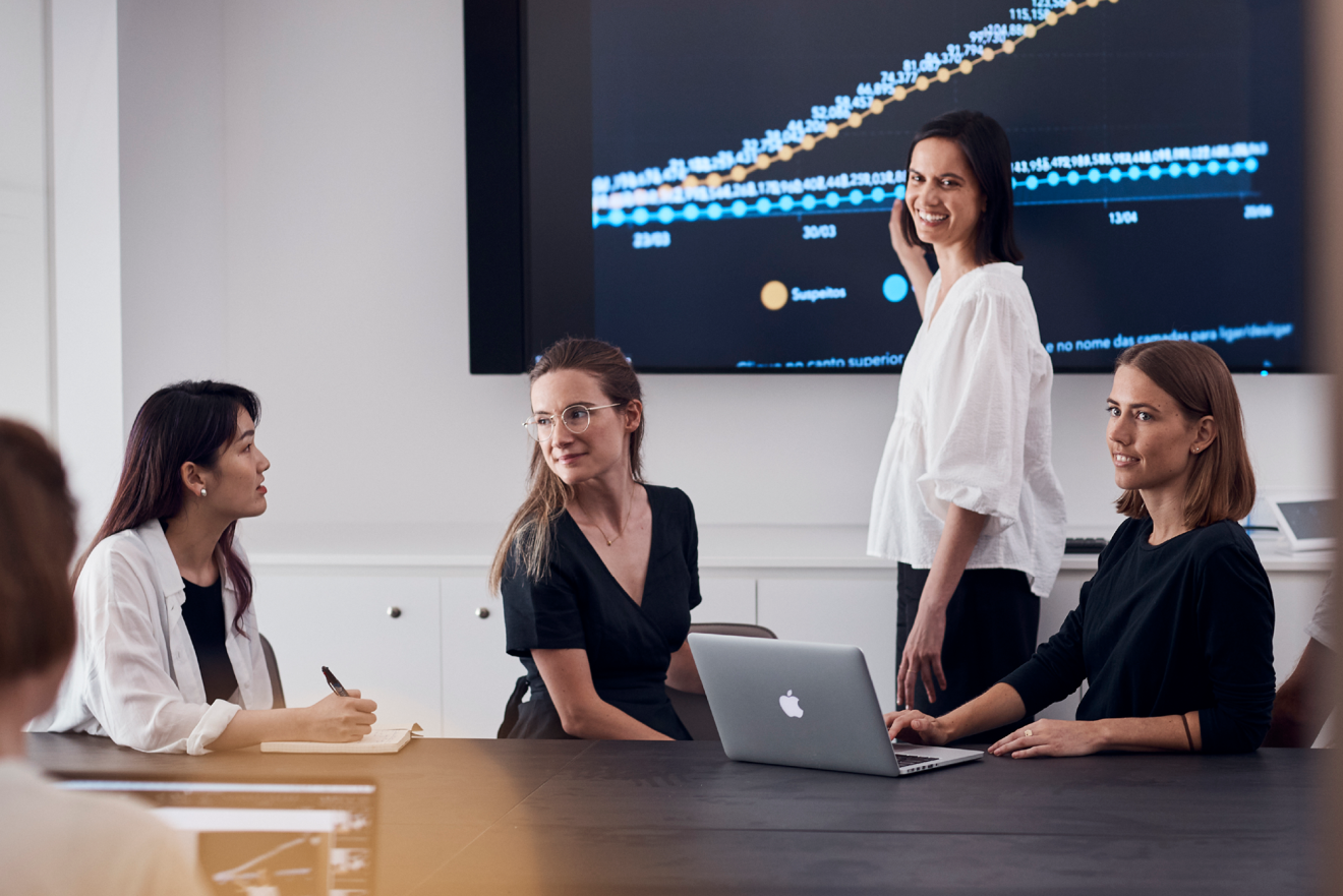 Group of women in conference room in front of presentation screen.