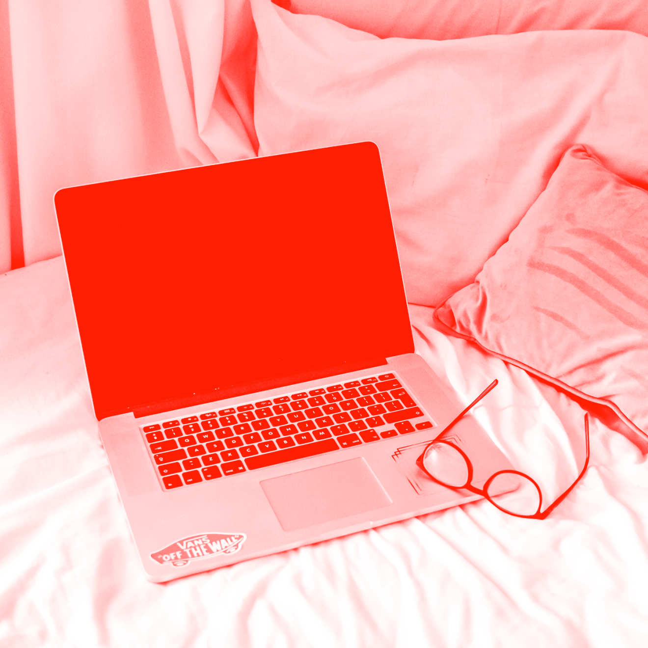 Laptop and glasses on a bed.