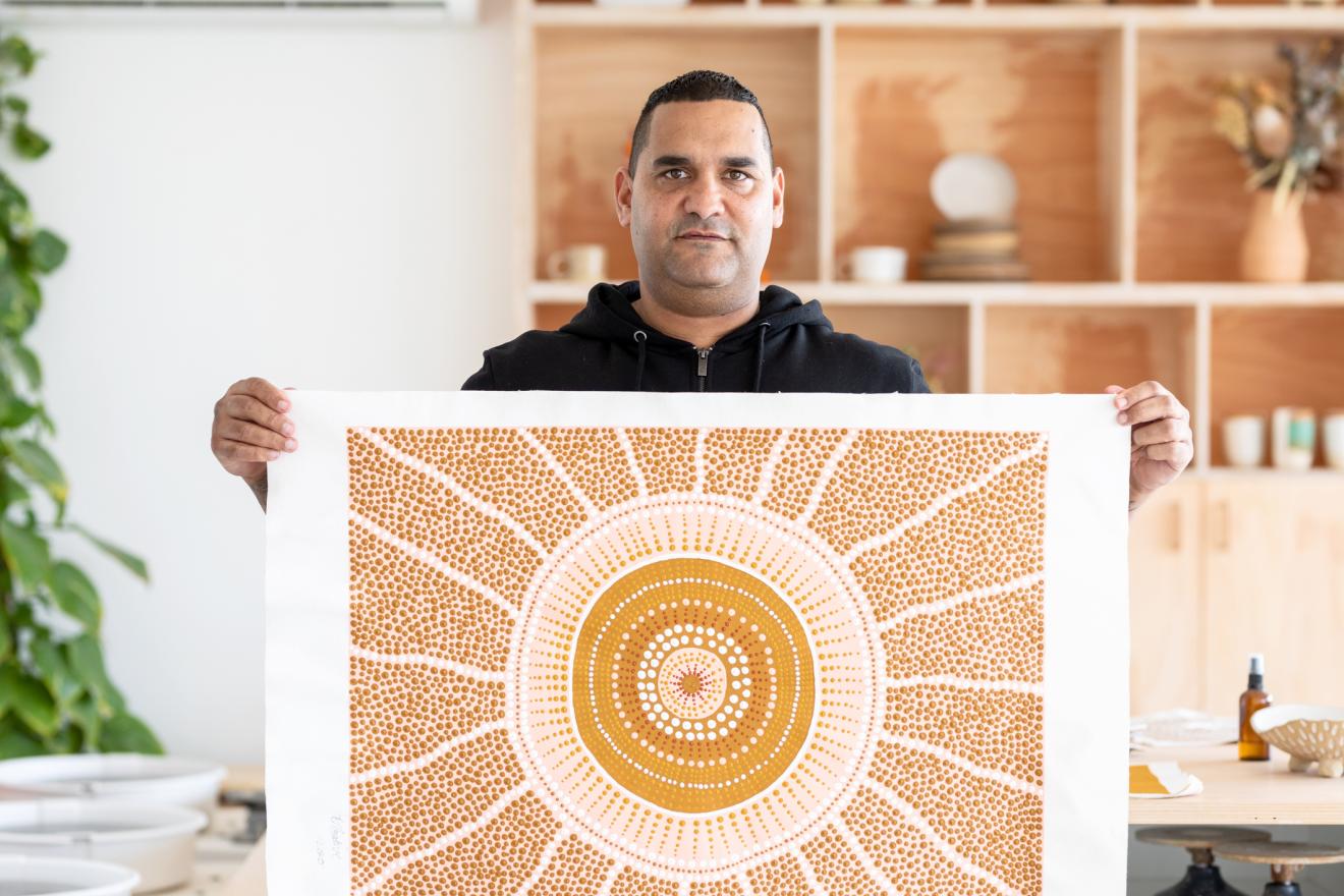 An aboriginal man shows a painting
