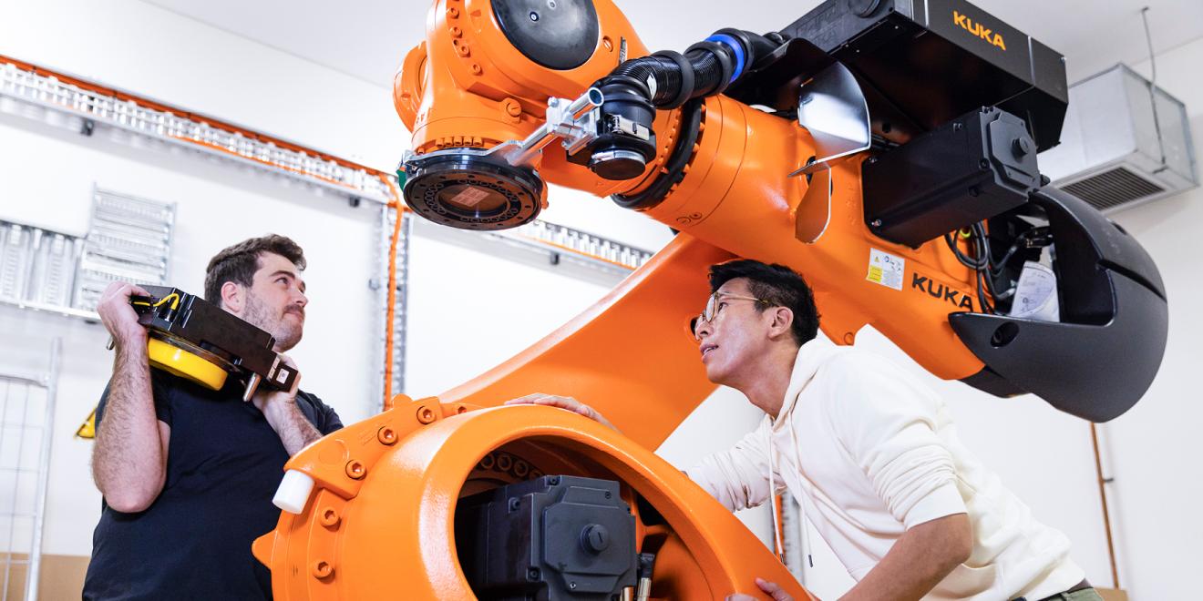 A student and lecturer looking at large robotic machine