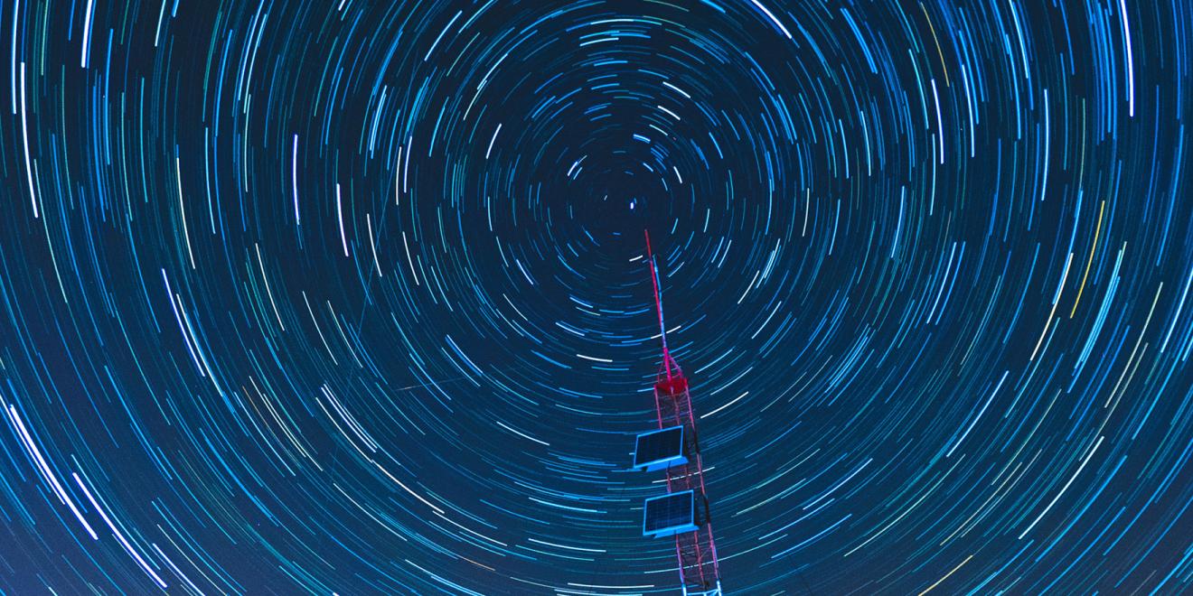 Time lapse of stars appearing as streaks rotating around an antenna