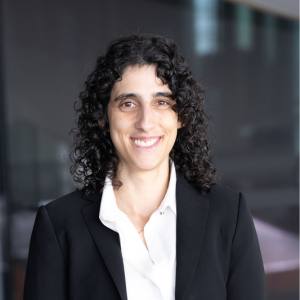 Catarina Moreira, black curly hair, white collared shirt and black suit jacket