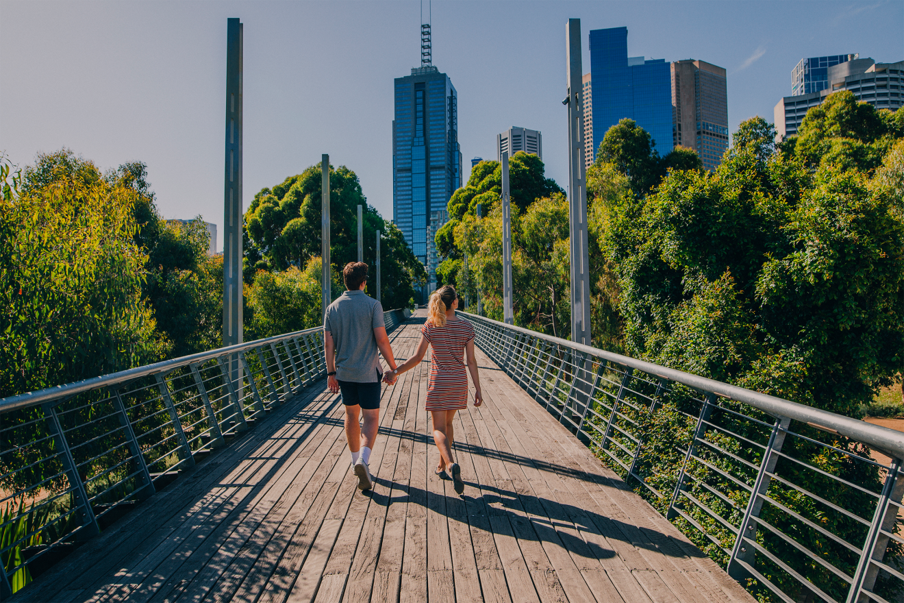 A young couple holding hands, walking down a bridge in Melbourne