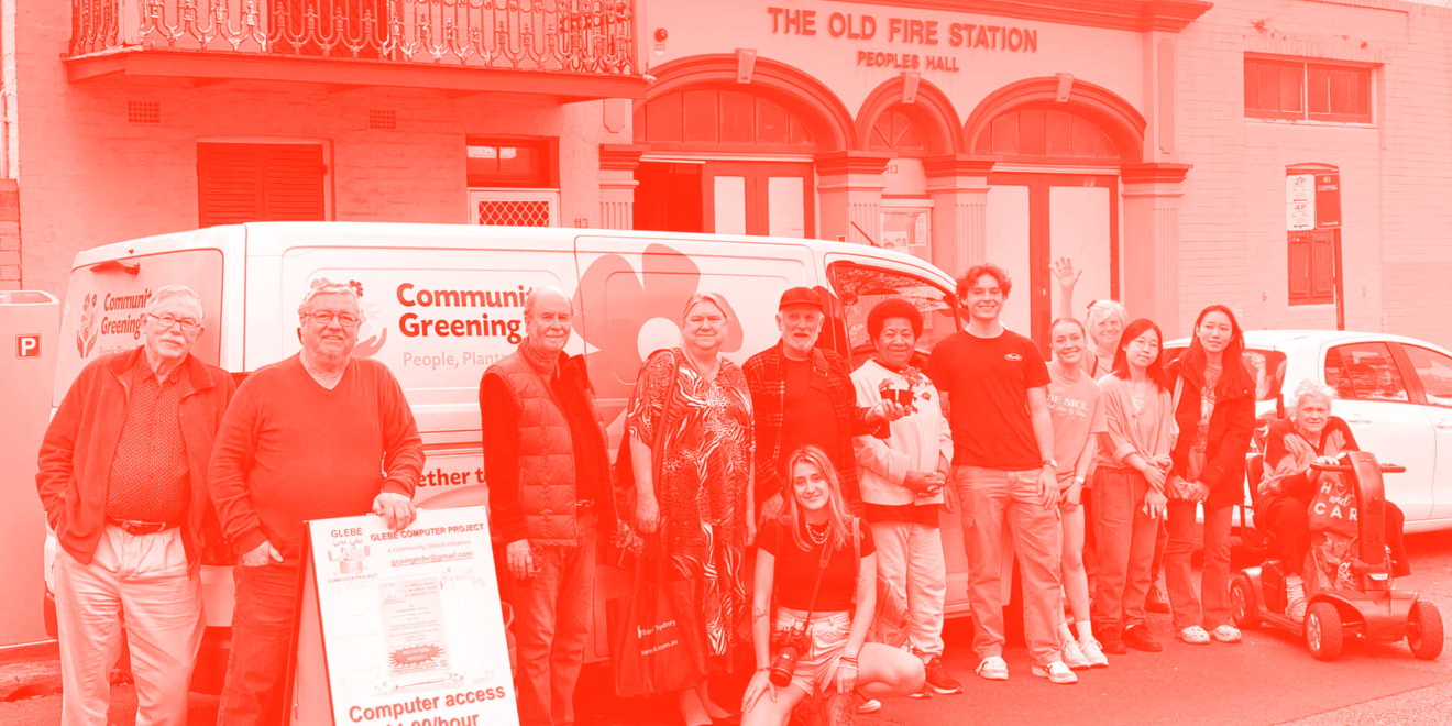 A group of community members and students stand together outside a community van and the old fire station in Glebe
