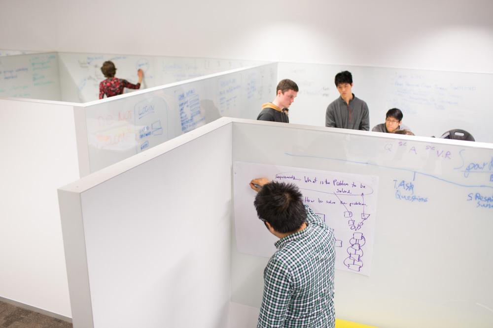 Students write on wall-to-wall white boards in the Software Development Studio to develop ideas