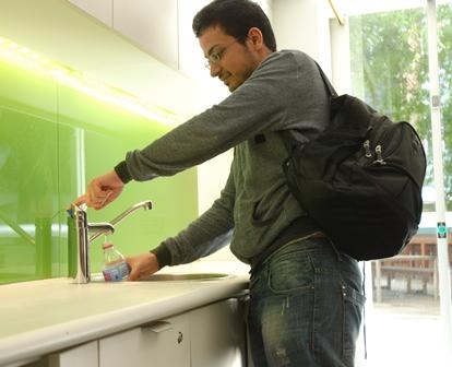 Student filling water bottle in building 5 student lounge