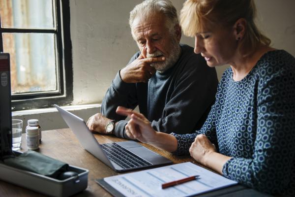 Older man working at laptop with woman