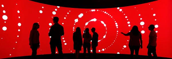 Silhouettes of seven students against a red screen background inside the UTS Data Arena