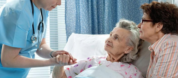 A woman in hospice care holding hands with a nurse