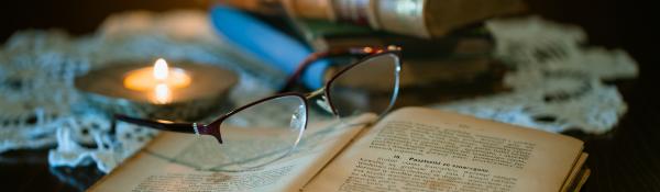 Glasses and an old open book with a candle