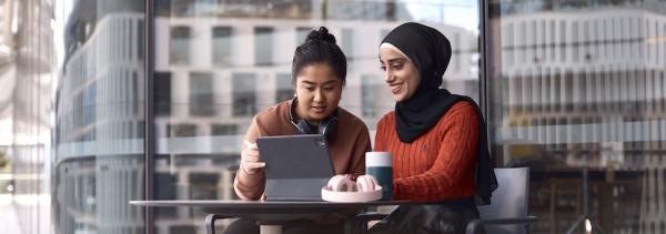 UTS Students looking at laptop on campus with headphones and reusable coffee cup