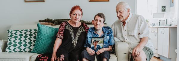 Family on a couch holding a photo of Lawrence Vidoni
