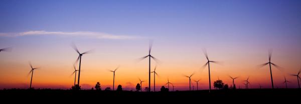 A view of a windfarm at sunset with a blue sky and bright orange horizon