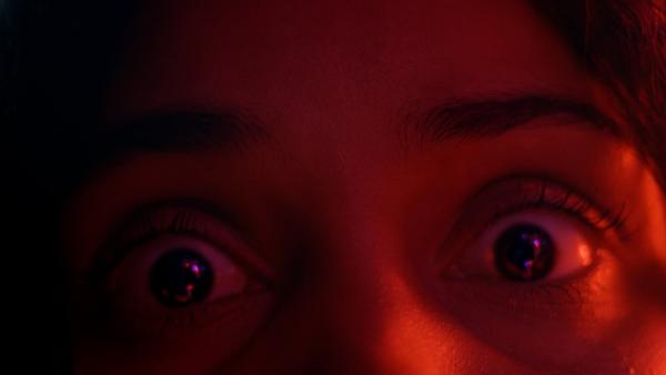 Ultra close-up of a woman's shocked eyes with a red overlay