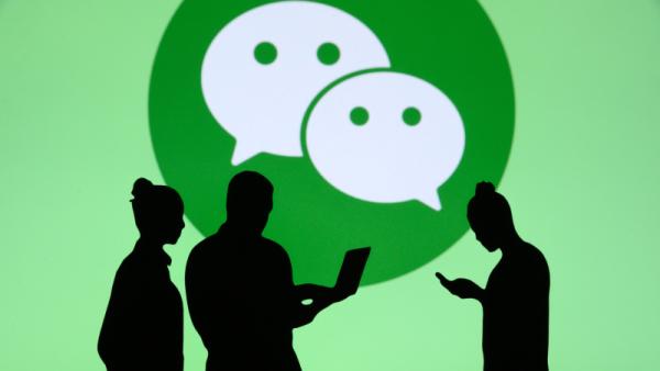 Group of business people chat on mobile phone and laptop. WeChat logo in background