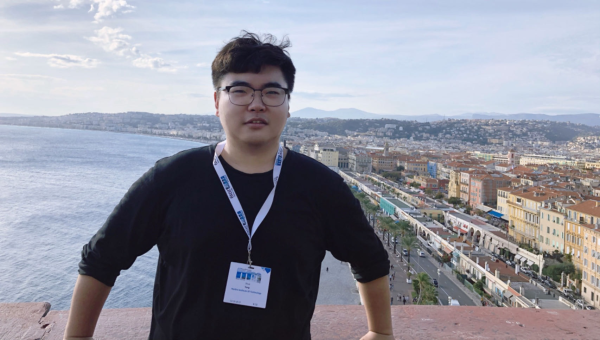Student Shuo Yang standing with city and beach skyline in background