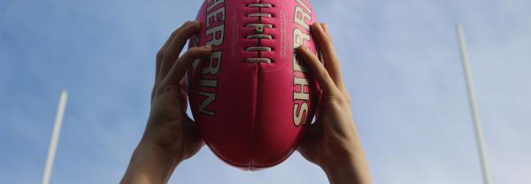 Hands catching pink AFL ball