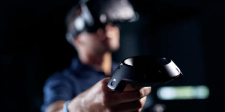 Man wearing VR headset and controller in dark room