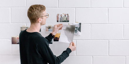 Man pinning photographs to wall