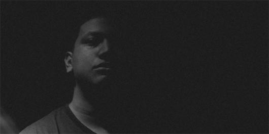 Black and white image of young man staring at camera.