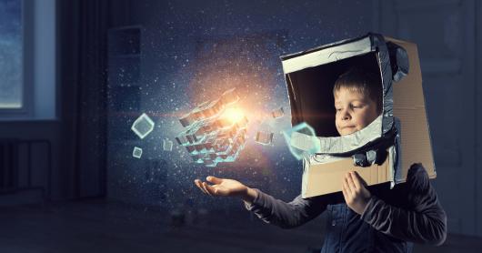 image of boy in cardboard helmet interacting with light-filled boxes