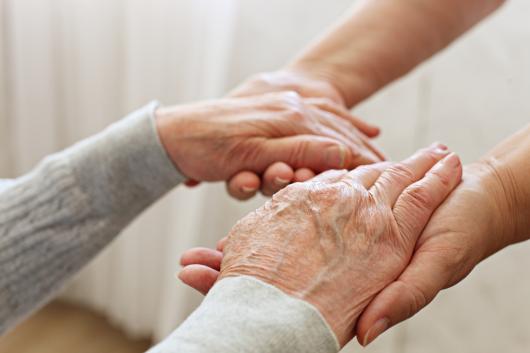 Elderly hands being held by younger hands