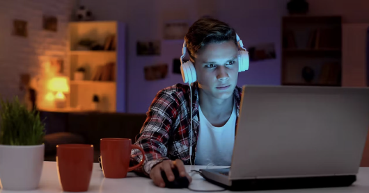 a young adult stares at a computer screen
