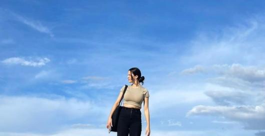 image of young woman standing against a blue sky background