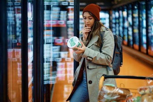 Woman looks at food label in the supermarket. Image: Adobe Stock
